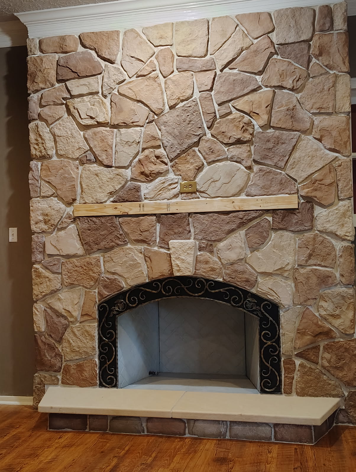 Arched stone fireplace masonry with iron surround in Tomball, TX