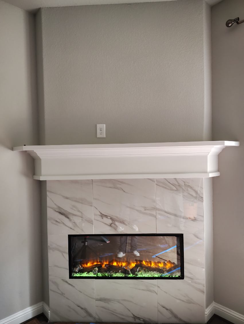 Linear electric fireplace set in marble-look tile with a white mantel in Sugar Land, TX