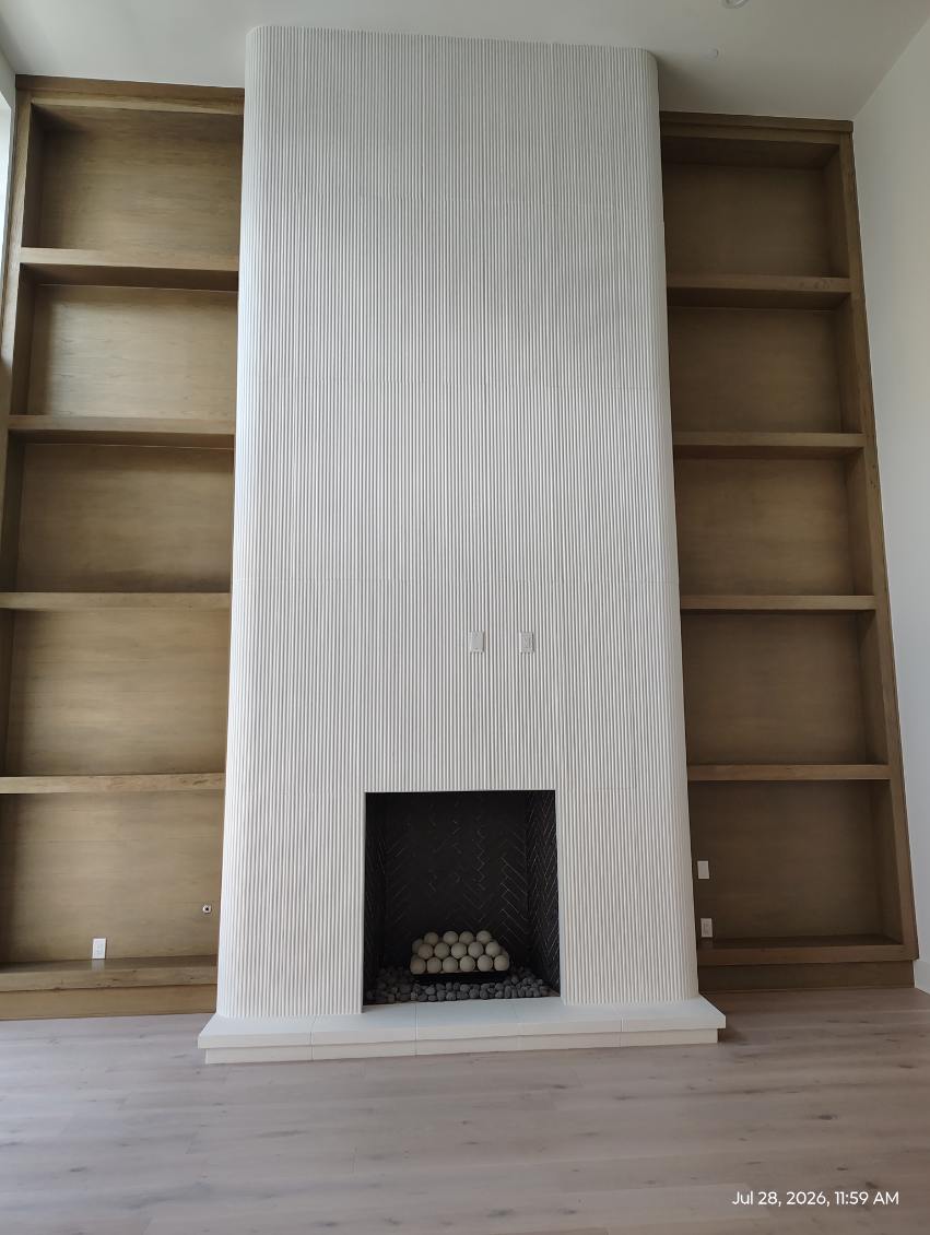 Finished white plaster fireplace with flanking built-in shelving in Houston, TX