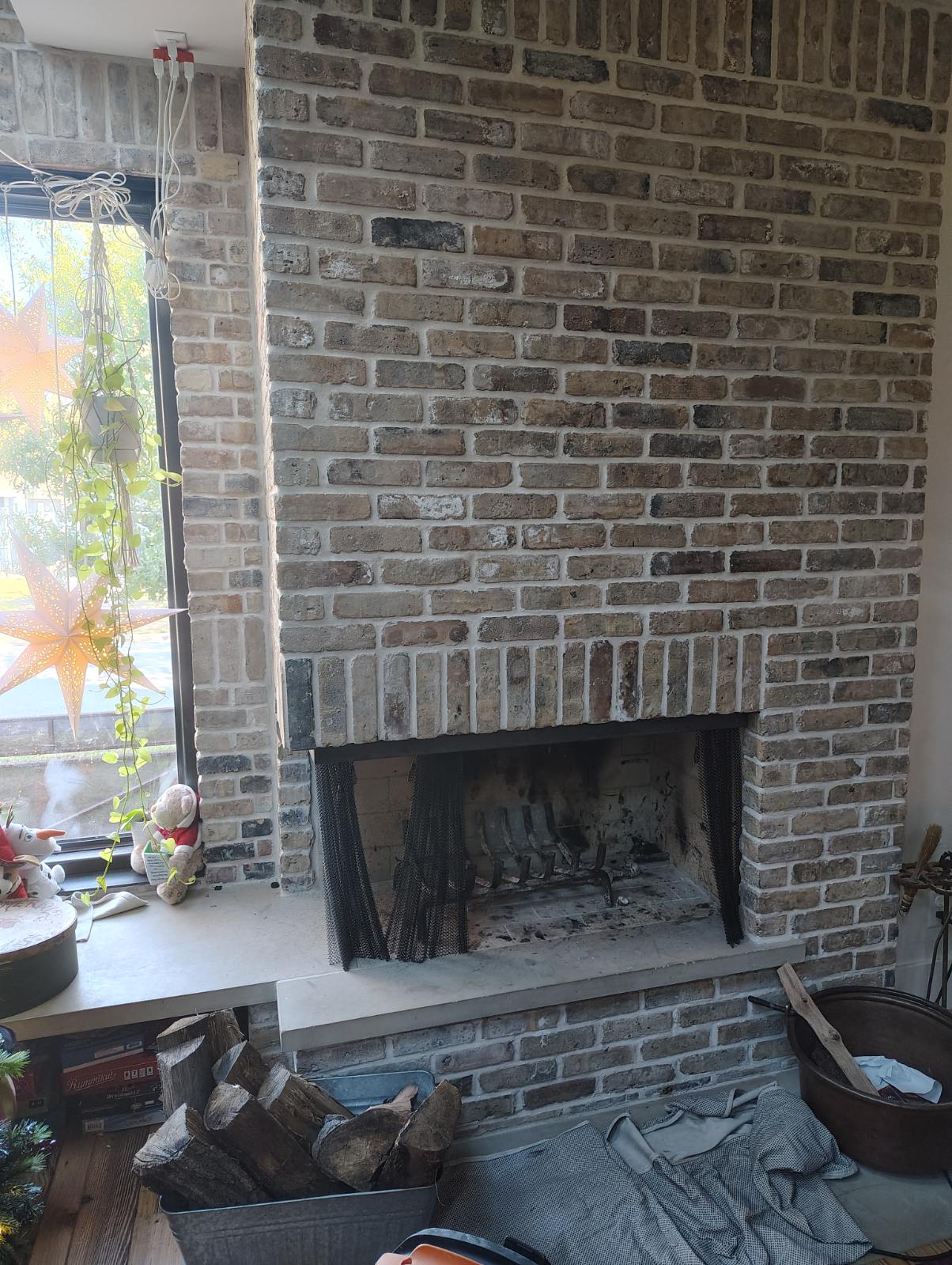 Floor-to-ceiling whitewashed brick fireplace with a stone hearth and wood-burning firebox in Houston, TX