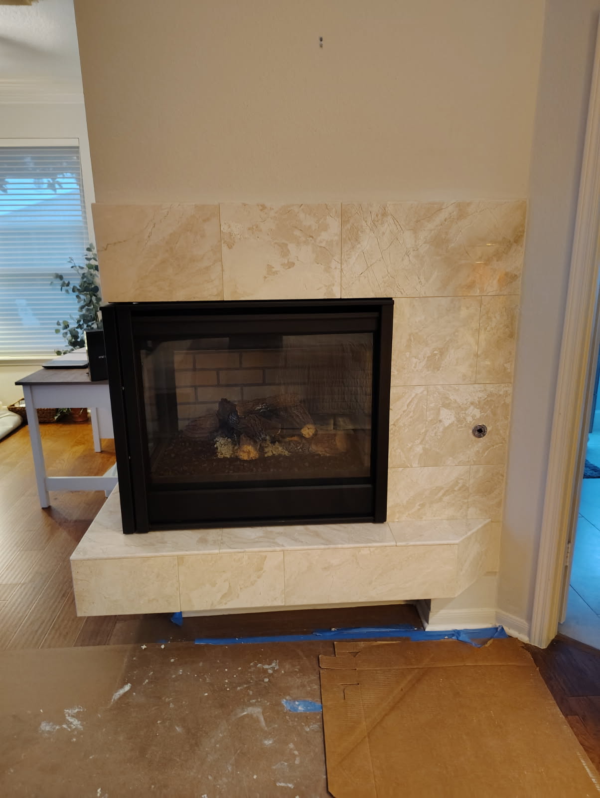Travertine tile fireplace surround and raised hearth around a see-through gas fireplace in Katy, TX