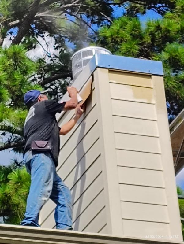 Technician fitting a new galvanized chase cover on a chimney in Spring, TX